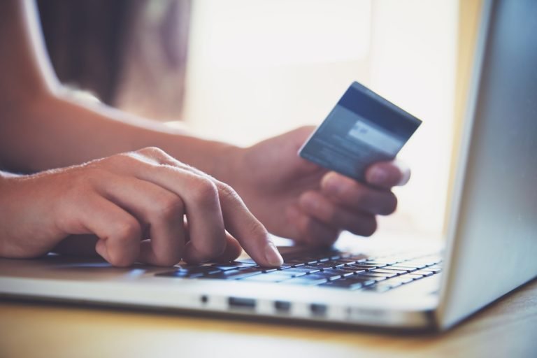 Person holding a credit card while typing on laptop