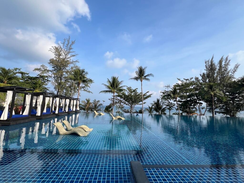Large hotel pool with cabanas to the left and palm trees ahead