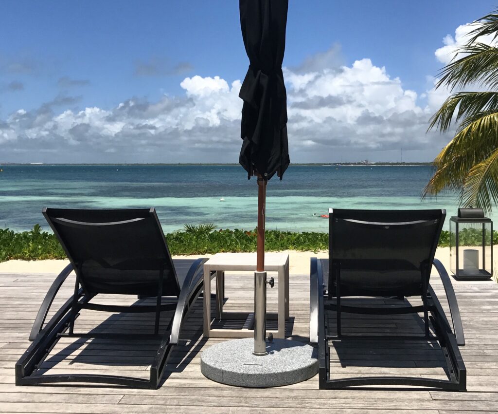 Two lounge chairs on a deck facing the ocean