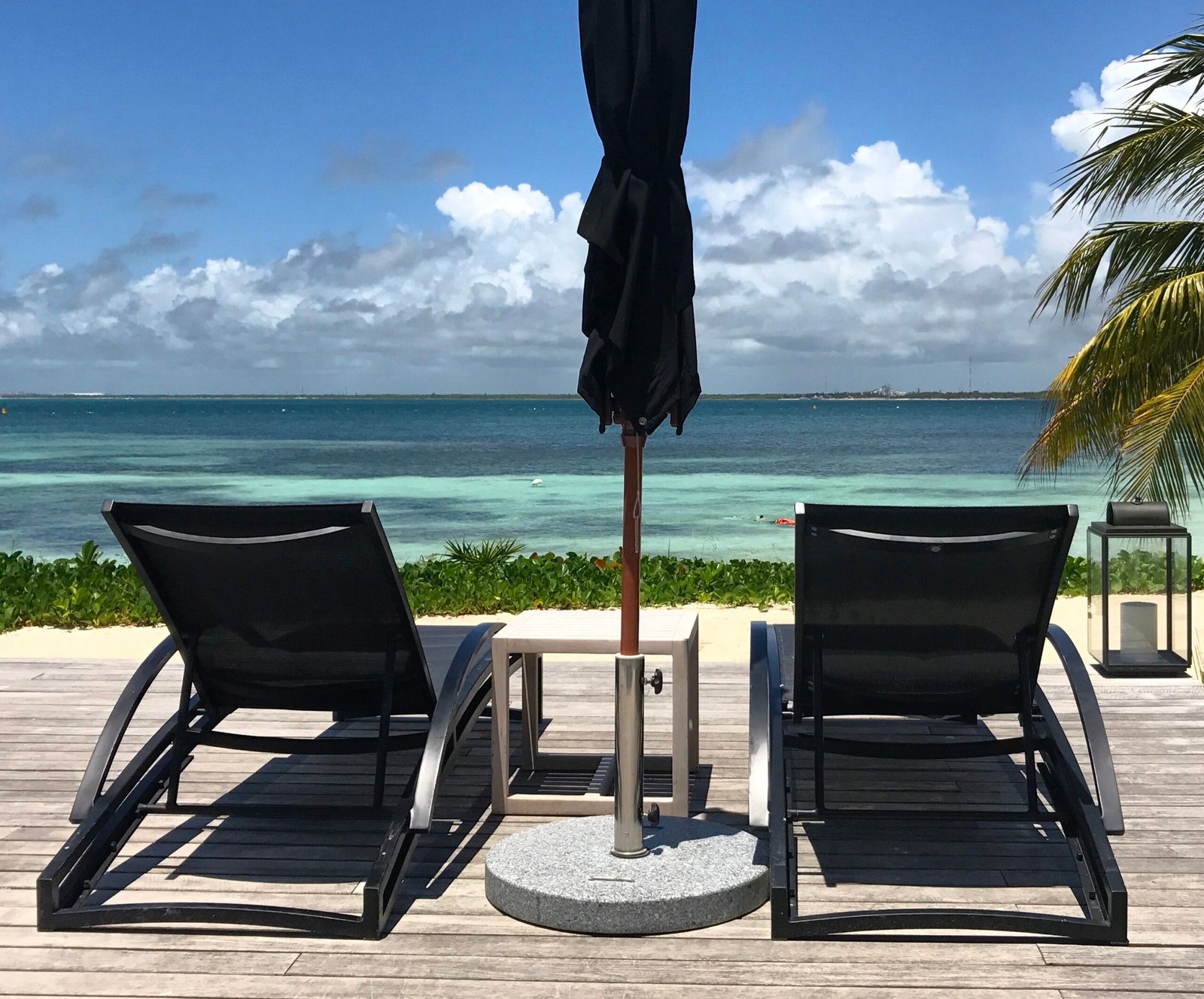 Two lounge chairs on a deck facing the ocean